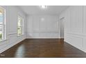 Elegant living room with decorative wall trim, gleaming hardwood floors, and abundant natural light from the large window at 7502 Latteri Ct, Raleigh, NC 27613