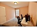 Home office with plush carpet, a white desk and an adjustable window blind at 83 Mariners Point Way, Garner, NC 27529