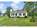Charming white home featuring black shutters, a cozy front porch, and a well-maintained landscaped lawn at 107 Winter Ct, Selma, NC 27576