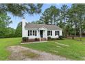 Charming white home featuring black shutters, a cozy front porch, and a well-maintained landscaped lawn at 107 Winter Ct, Selma, NC 27576