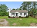 Charming white home with black shutters, a cozy front porch, and landscaped lawn under a clear blue sky at 107 Winter Ct, Selma, NC 27576