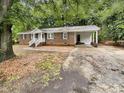 Ranch-style house with a brick exterior, carport, and driveway surrounded by lush trees at 1508 Hodge Rd, Knightdale, NC 27545