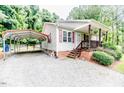 Exterior showcasing carport, tidy landscaping and charming front porch with brick foundation at 1605 Goldsboro Ave, Sanford, NC 27330