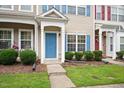 Charming front entrance with a blue door, manicured lawn and vibrant green shrubs at 1642 Holly Grove Way, Durham, NC 27713