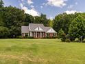 Inviting brick home with a manicured lawn and mature trees creating a serene setting at 2819 Russell Mcpherson Rd, Burlington, NC 27215