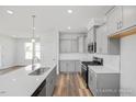 Bright, open kitchen featuring gray cabinetry, stainless appliances, and a center island with sink at 324 Longleaf Glen Court, Zebulon, NC 27597