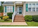 Inviting front porch featuring brick steps, white railings, and a decorative front door with a wreath at 402 Hearthstone Dr, Nashville, NC 27856