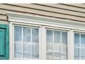 Close-up of a window featuring detailed trim, turquoise shutters, and a view of the sky reflecting in the glass at 402 Hearthstone Dr, Nashville, NC 27856