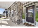 Inviting front porch with stone columns, a stylish front door, and decorative plants at 713 Ramsours Mill Dr, Holly Springs, NC 27540