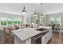 Open-concept kitchen with island, stainless steel sink, and a view into the living and dining areas at 728 Peninsula Forest Pl, Cary, NC 27519
