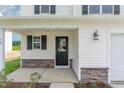 Inviting front entrance featuring a stylish black door, stone accents, and a cozy covered porch at 74 W Emily Gardens Dr, Selma, NC 27576