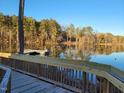 Scenic view of the lake from the wooden dock, with calm waters and lush trees reflecting the sunlight at 75 Slippery Elm Rd, Youngsville, NC 27596