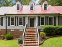 Beautiful home with a vibrant red roof, complemented by lush greenery and brick accents at 101 Joel Ct, Cary, NC 27513