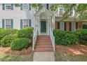 Charming two-story home with white siding, blue shutters, landscaped yard, and inviting brick steps at 1701 Berwickshire Cir, Raleigh, NC 27615