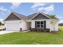 Charming single-story home showcasing a well-maintained lawn and stylish stone detailing at 30 Chloe Ct, Selma, NC 27576
