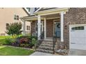 Inviting front porch with brick steps, white columns, and a beautifully landscaped garden at 3032 Curling Creek Drive Dr, Apex, NC 27502