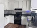 Modern kitchen with white cabinetry, gray backsplash, black appliances, and sleek countertops creating a clean and stylish space at 3624 Meadow Creek Ln, Raleigh, NC 27616