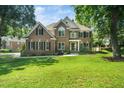 Beautiful two-story brick home with lush green lawn and mature trees providing ample shade at 3811 Cottonwood Dr, Durham, NC 27705