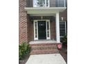 Elegant black front door framed by white columns and sidelights with brick steps at 3811 Cottonwood Dr, Durham, NC 27705