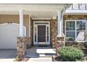 Inviting front porch with stone pillars, a dark brown door, and a sidelight at 413 Westfalen Dr, Cary, NC 27519