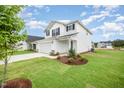 Charming two-story home featuring a two-car garage and well-maintained lawn with fresh landscaping at 58 W Emily Gardens Dr, Selma, NC 27576
