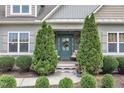 Inviting front porch with twin evergreens framing an entryway with a teal front door at 71 Smithsanders Ct, Smithfield, NC 27577
