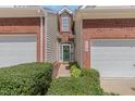 Charming townhome entrance featuring a green door adorned with a wreath and manicured bushes at 8004 Thrush Ridge Ln, Raleigh, NC 27615