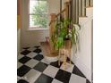 Hallway featuring black and white tile flooring, stairs, and a plant near a window providing natural light at 1113 Mordecai Dr, Raleigh, NC 27604