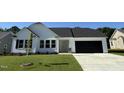 Attractive one-story house showcasing a manicured lawn, black garage door, and simple landscaping at 128 Oakfield Trace Dr, Four Oaks, NC 27524