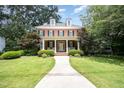Attractive brick home with lush landscaping, a welcoming front porch, symmetrical design, and dormer windows at 1414 Park Dr, Raleigh, NC 27605