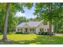 Charming white two-story home with manicured lawn and mature trees under a blue sky at 300 Williamston Ridge Dr, Youngsville, NC 27596