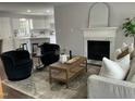 Comfortable living room with fireplace, open to the kitchen, featuring modern decor, and hardwood floors at 3045 Creek Moss Ave, Wake Forest, NC 27587
