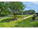 Scenic landscape with a mature tree, black fencing, and lush green grass at 633 Fleming Rd, Youngsville, NC 27596
