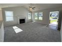 Bright living room featuring neutral carpet, a fireplace, large windows, and an open doorway at 91 Oakfield Trace Dr, Four Oaks, NC 27524