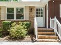 Close-up of the home's brick entrance with white door and trim, enhanced by lush landscaping at 100 Upton Ct, Garner, NC 27529