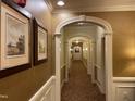 Hallway featuring decorative arches, neutral paint, framed artwork, and patterned carpet at 10411 Rosegate Court # 6, Raleigh, NC 27617