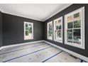 A room with dark gray walls and white trim, featuring three large windows letting in natural light at 1225 Dixie Trl, Raleigh, NC 27607