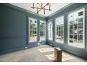 Living room featuring trim, paneled walls, multiple windows, and stylish lighting fixture at 1229 Dixie Trl, Raleigh, NC 27607
