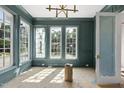 Living room featuring trim, paneled walls, multiple windows, stylish lighting fixture, and a doorway at 1229 Dixie Trl, Raleigh, NC 27607