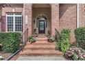 Inviting front porch with brick steps, black railings and planters overflowing with colorful flowers at 12412 Mayhurst Pl, Raleigh, NC 27614