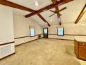 Open living area featuring exposed wood beams, neutral carpet, and natural light from large windows at 1306 Oakridge Ave, Henderson, NC 27536