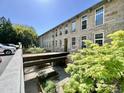 View of building with stone facade, large windows, landscaped grounds, and courtyard at 1500 River Mill Dr # 310, Wake Forest, NC 27587