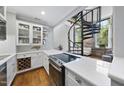 Modern kitchen featuring stainless steel appliances, white cabinets, and a view into the living area with spiral staircase at 1500 River Mill Dr # 310, Wake Forest, NC 27587