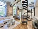 Inviting living room with a spiral staircase, stone walls, hardwood floors, and lots of natural light from large windows at 1500 River Mill Dr # 310, Wake Forest, NC 27587