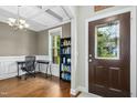 Inviting entryway featuring hardwood floors, wainscoting, and a decorative front door, leading into a cozy office space at 210 Water Oak Way, Louisburg, NC 27549