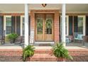 Inviting front porch with rocking chairs, ferns, and a decorative wooden front door at 2925 Dargan Hills Dr, Wake Forest, NC 27587