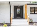 Modern black front door with glass pane and stylish white stairs leading to the entrance at 3032 Dixon Rd, Durham, NC 27707