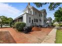 Backyard brick patio with a grill, stairs to an upper level and mature landscaping at 309 W Divine St, Dunn, NC 28334
