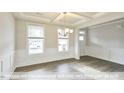 Bright dining room with a tray ceiling, chandelier, wainscoting, hardwood floors, and large windows at 405 Falls Bluff Dr, Wake Forest, NC 27596