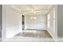 Lovely dining room featuring a tray ceiling, elegant chandelier, wainscoting, and hardwood floors at 405 Falls Bluff Dr, Wake Forest, NC 27596